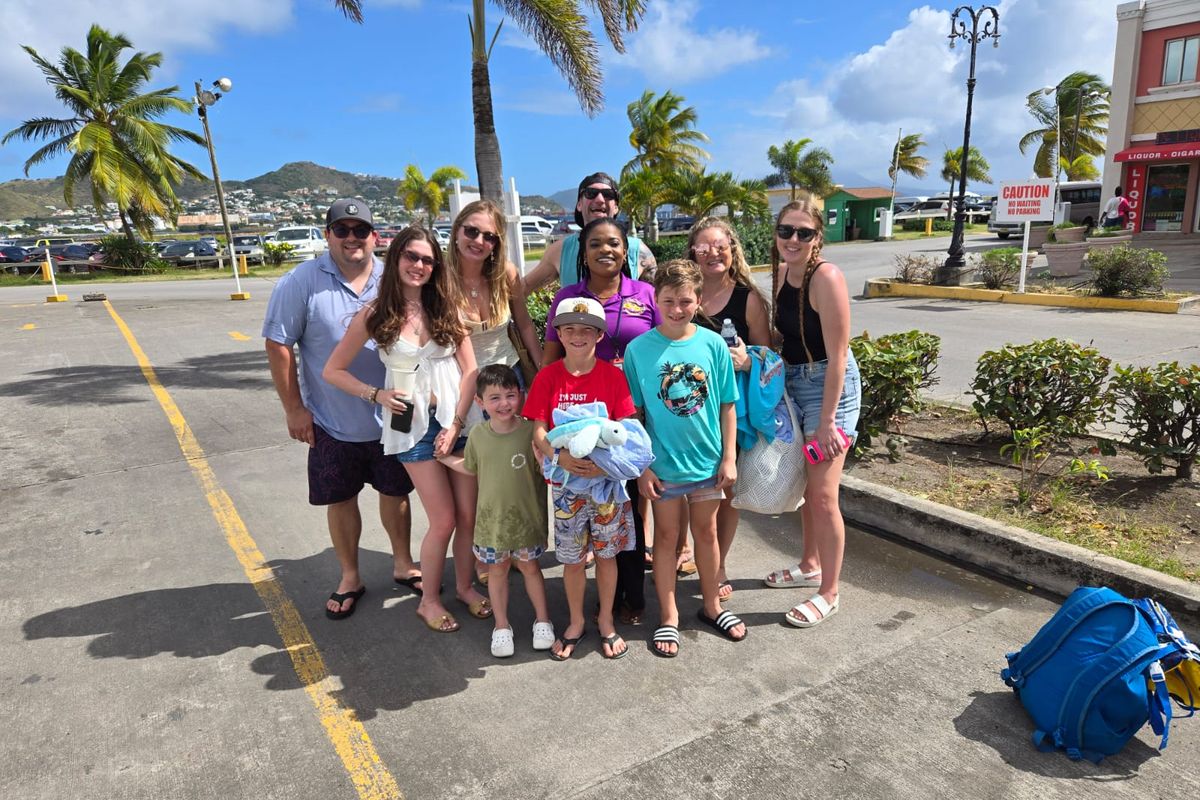 Mechiel Francis Dunrod standing with a cruise family of adults and children before a tour in Basseterre, with palm trees behind them