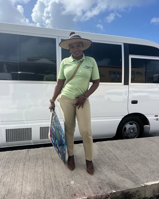 Mechiel in a green shirt and sun hat standing beside the white Extra Mile bus